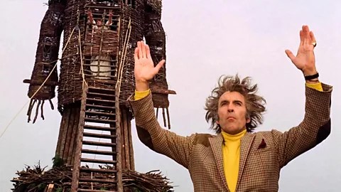 Christopher Lee as Lord Summerisle, hands raised, in from of the wicker man